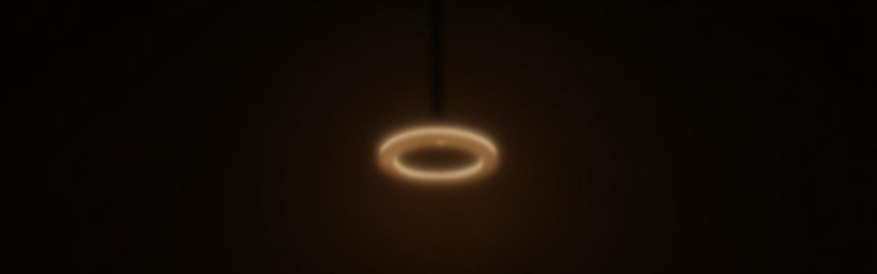 The 'Aura' Ring Pendant, a minimalist halo of warm light floating in a modern room.